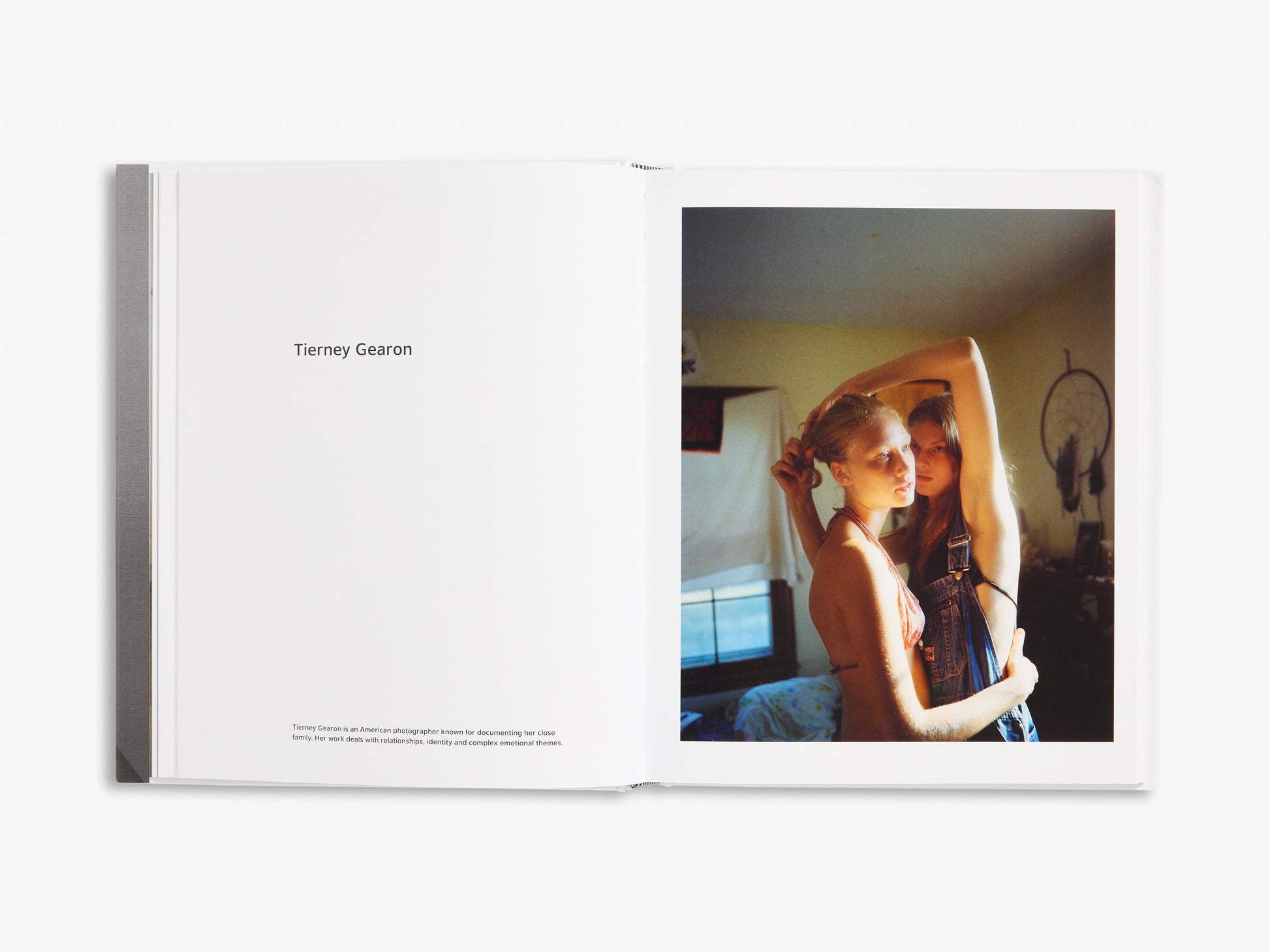 Open book showing a photograph of two people in a room with a dreamcatcher in the background.