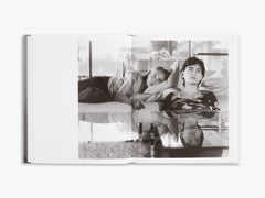 Open book showing a black and white photograph of two people lying on a sofa.