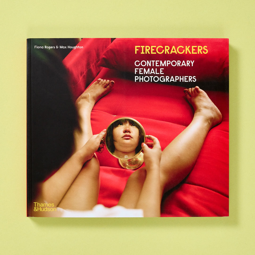 Book cover of 'Firecrackers: Contemporary Female Photographers' with a person lying on a red surface.